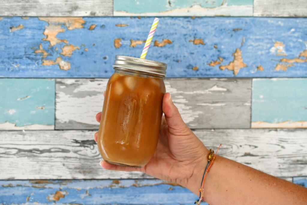 Kombucha w diecie sportowca 2 dlon trzymajaca sloik mrozonej kawy ze slomka